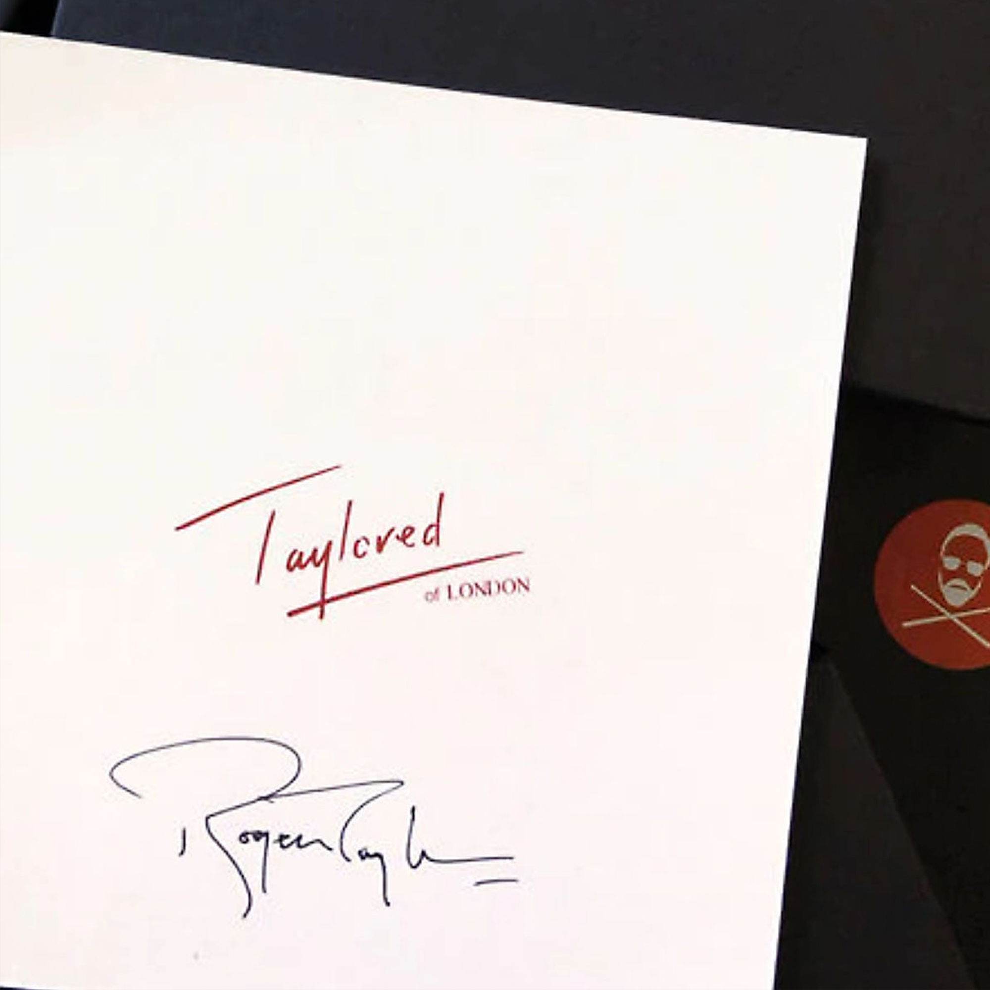 White card with 'Taylored of London' branding and a signature, featuring a red circular logo