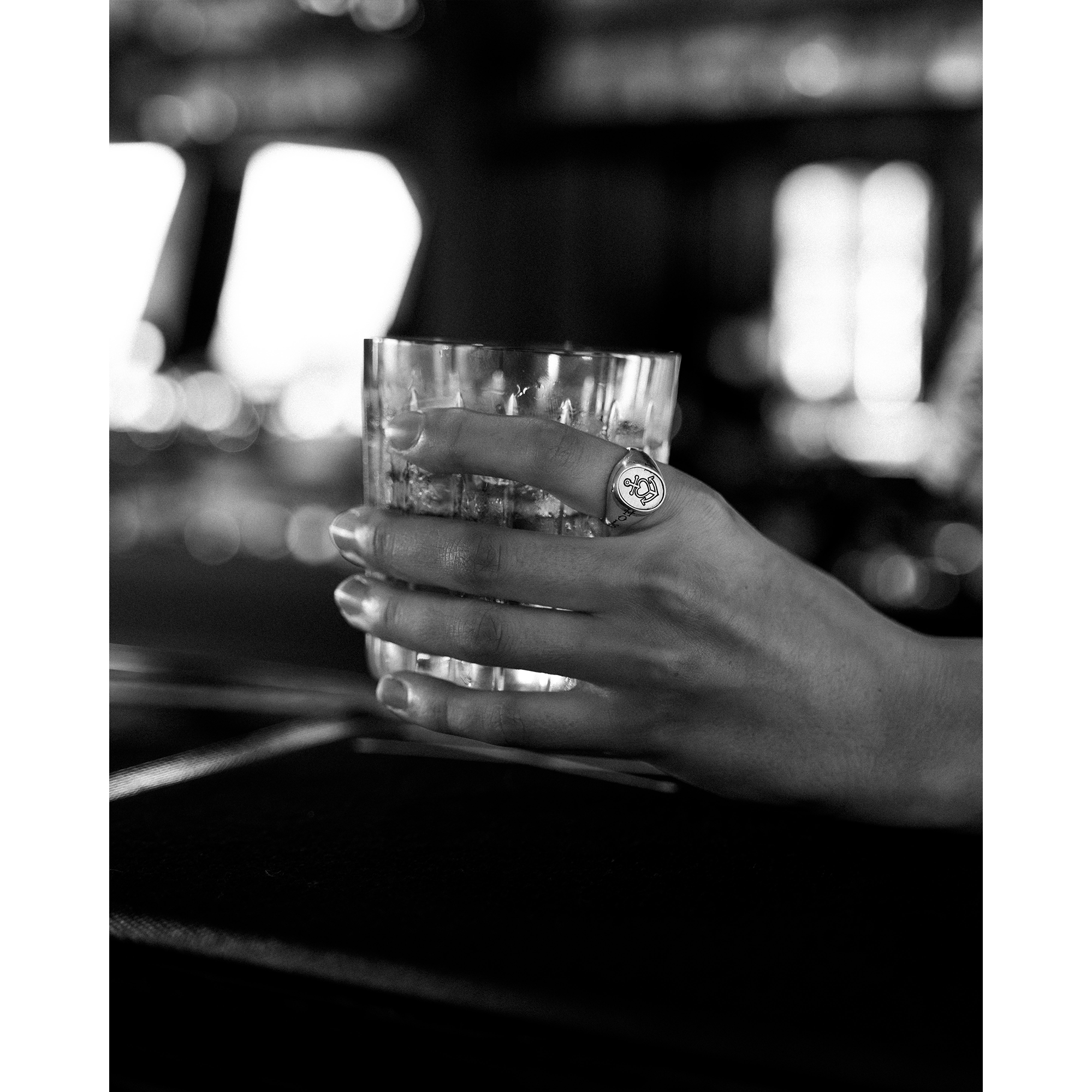 Hand holding a glass and wearing the Hold Fast Ring 